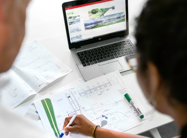 Software de gestión para pymes: profesional revisando planos junto a un portátil